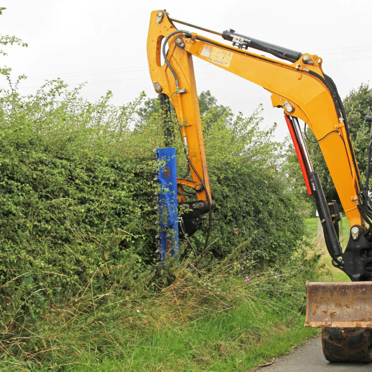 Auger Torque Hedge Trimmer attached to an excavator trimming a hedge